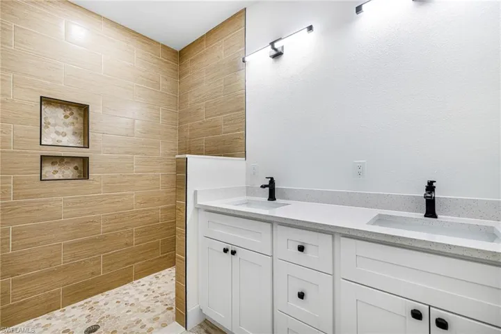 Bathroom with double vanity, a sink, and a walk in shower