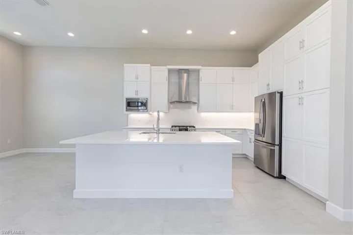 Spacious kitchen featuring an expansive island, white cabinetry, stainless steel appliances, and recessed lighting