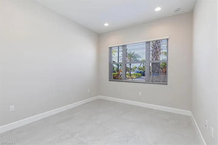 Recessed ceiling lighting, window with horizontal blinds, light-toned wall paint, and tile flooring