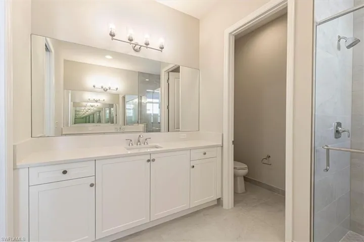 Expansive vanity with a single undermount sink, white cabinetry, and a large mirror