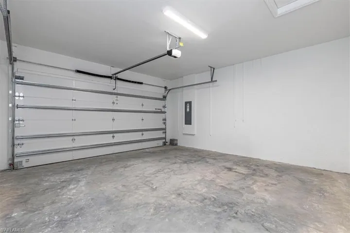Spacious garage with a concrete floor, white painted walls, and an automatic overhead door