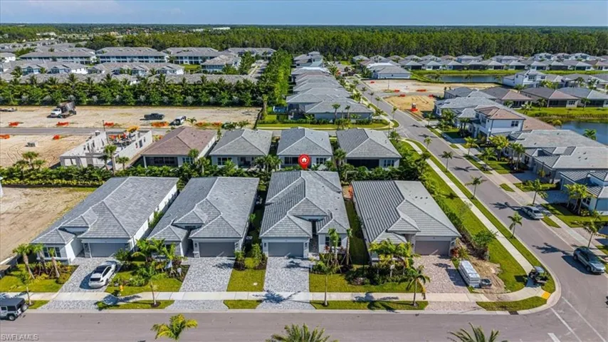 Modern residential community featuring paver driveways, attached garages, and mature palm tree landscaping