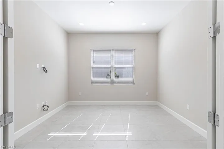 Recessed lighting, window with horizontal blinds, light-toned walls, and tile flooring