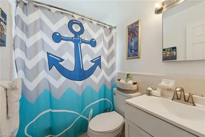 Full bathroom with vanity, toilet, curtained shower, and tile walls
