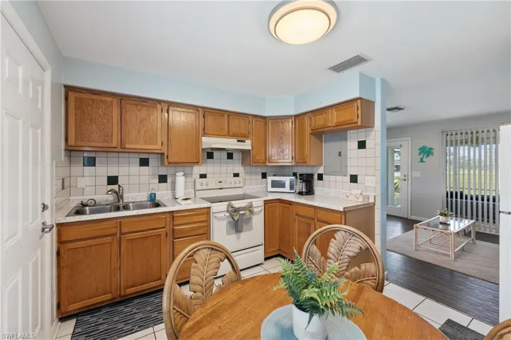 Kitchen featuring white appliances, a sink, under cabinet range hood, and light countertops