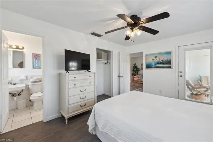 Bedroom with dark wood-style flooring, a closet, a ceiling fan, ensuite bathroom, and baseboards