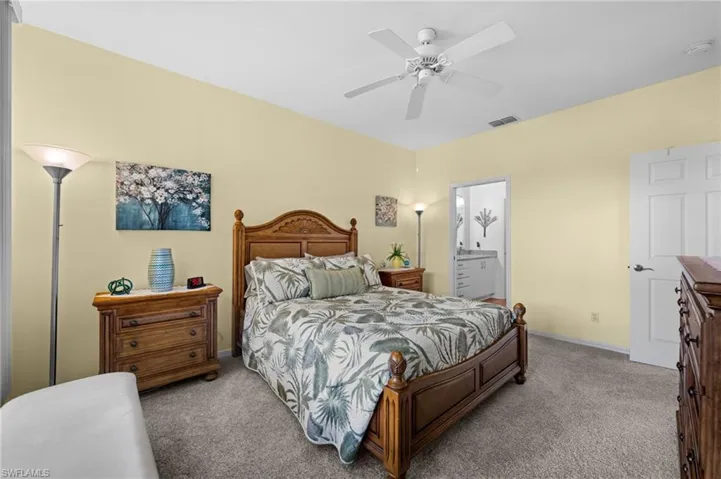 Carpeted bedroom with a ceiling fan, light yellow wall color, and a white paneled door