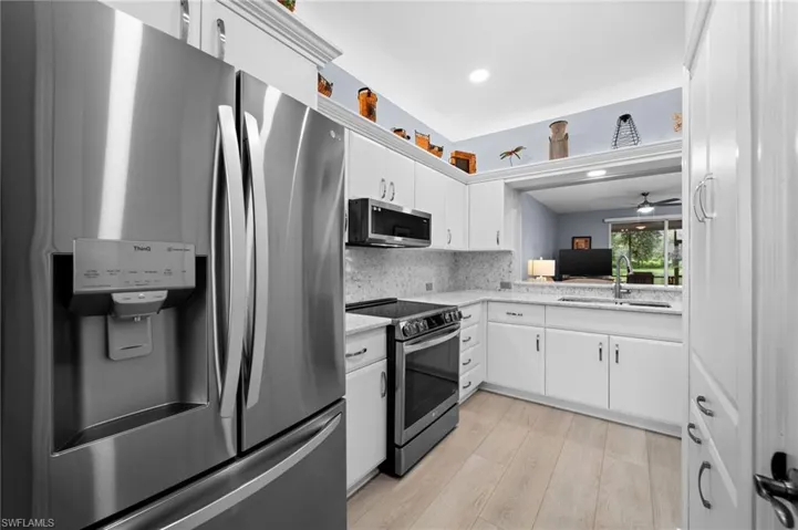 Stainless steel refrigerator, white cabinetry, integrated sink, and granite countertops