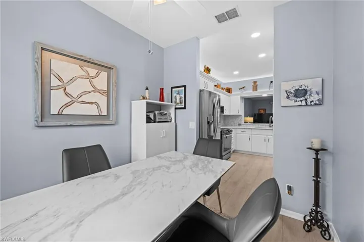 Wood-finish flooring extending into the kitchen, recessed lighting, and a ceiling fan