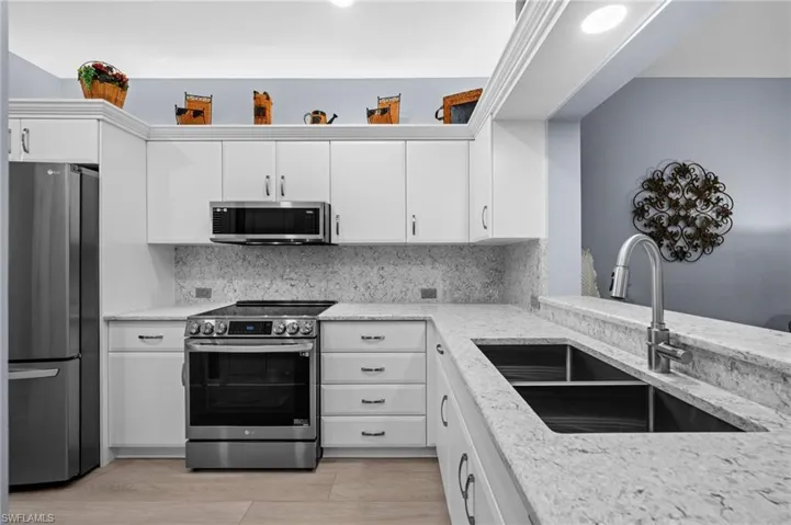 White cabinetry with upper storage, light-toned countertops, and a stainless steel oven