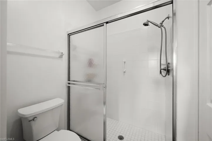 Shower enclosure with frosted sliding glass doors, white subway tile surround, tile mosaic flooring, and a brushed nickel shower head