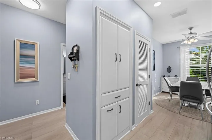 Recessed lighting, wood-finish flooring, white built-in cabinetry, and a ceiling fan
