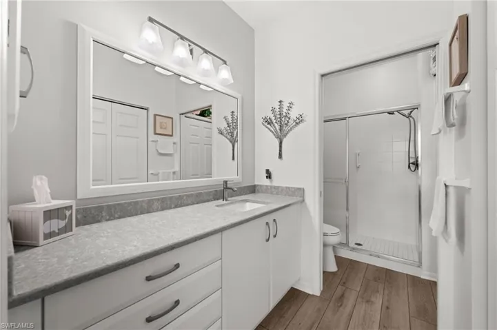 Extended vanity with light-toned countertop, integrated sink, and white cabinetry with drawer storage