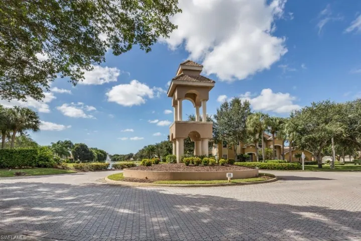 Paver roadway leading to a circular median with a tiered architectural feature