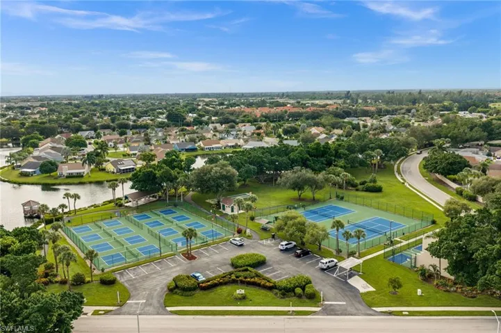Multiple tennis courts, a large paved parking area, and manicured landscaping are featured