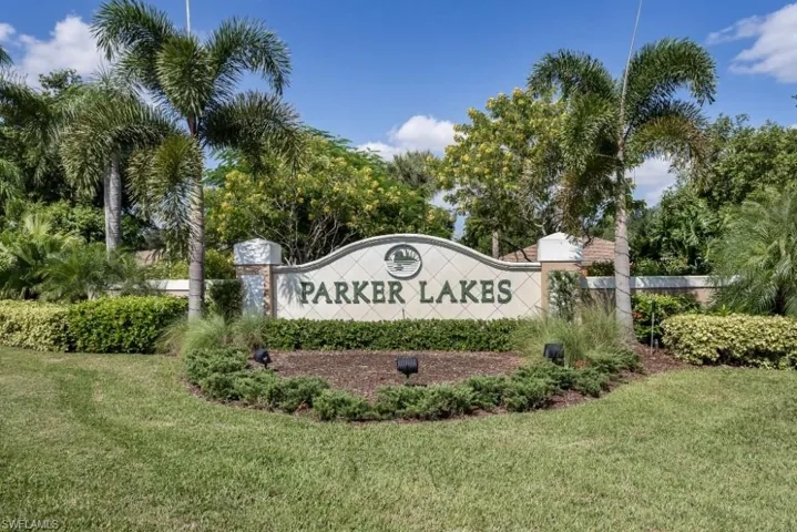 Parker Lakes community entrance with decorative signage, mature palm trees, lush landscaping, and manicured lawn