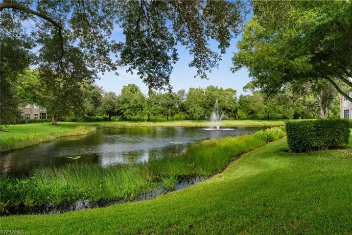 Expansive lawn area with a tranquil pond, featuring a central fountain and mature trees