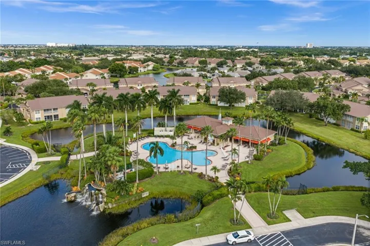 Community clubhouse with a freeform swimming pool, surrounding water features, and established palm trees