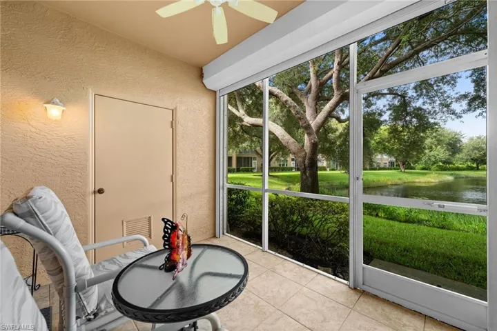 Screened outdoor area with tile flooring, an overhead ceiling fan, and a wall-mounted light fixture
