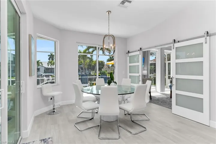 Kitchen featuring white cabinets, dishwasher, a peninsula, light stone countertops, and glass fronted cabinets