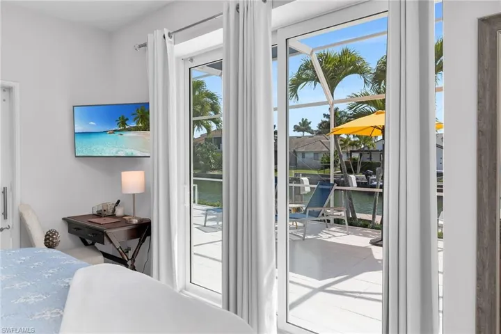 Swimming pool featuring a patio area, glass enclosure, outdoor dining space, a sunroom, and a water view