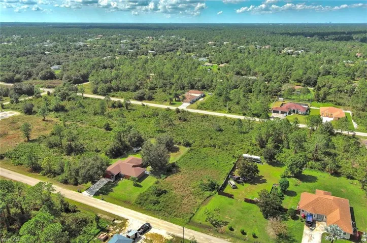 Aerial view of property and surrounding area with a forest