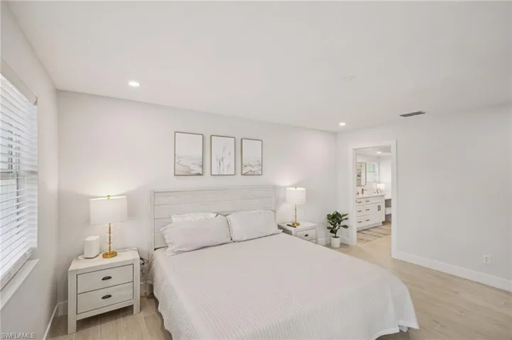 Bedroom with light wood-type flooring, recessed lighting, and ensuite bath