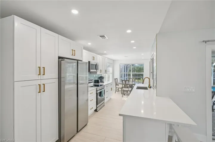Kitchen with stainless steel appliances, recessed lighting, white cabinets, light countertops, and light wood finished floors