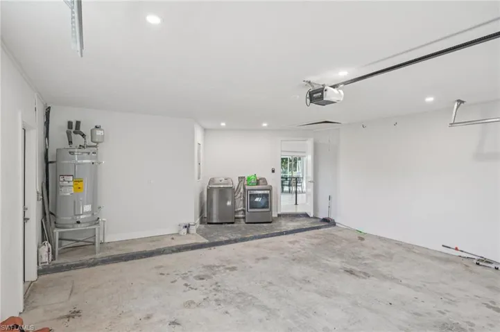 Garage with washing machine and clothes dryer, recessed lighting, strapped water heater, and a garage door opener