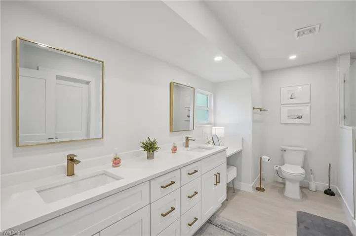 Bathroom with wood finished floors, double vanity, recessed lighting, and a shower