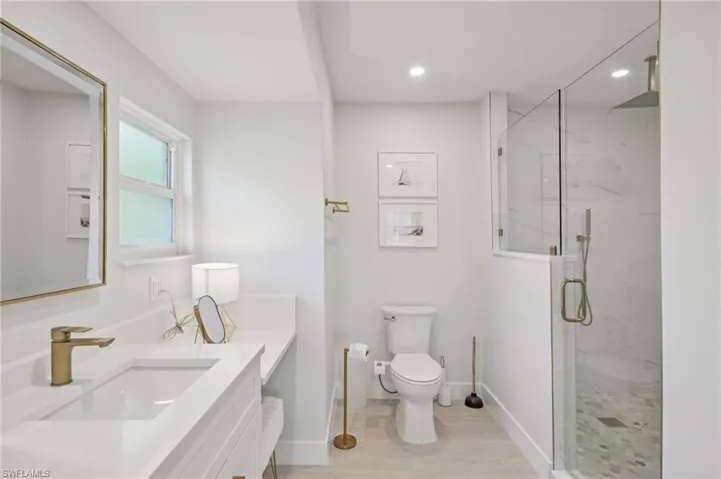 Bathroom featuring a marble finish shower, vanity, wood finished floors, and recessed lighting