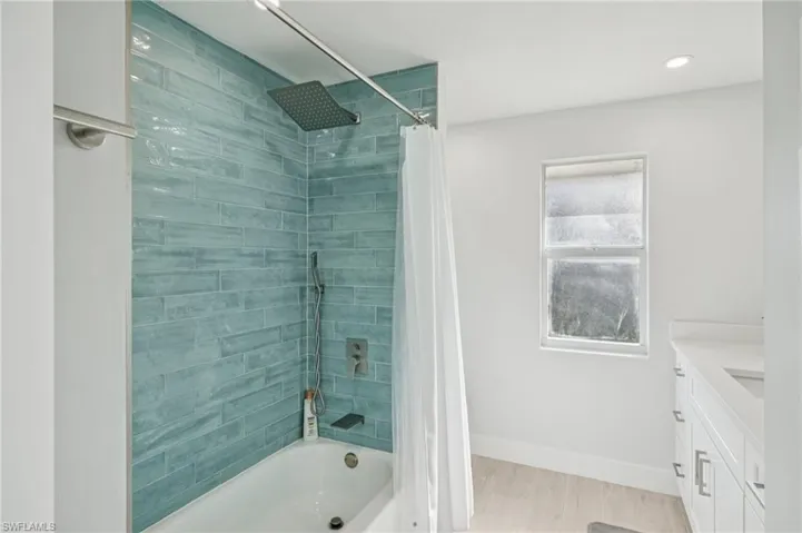 Bathroom featuring vanity, shower / tub combo with curtain, wood finished floors, and recessed lighting