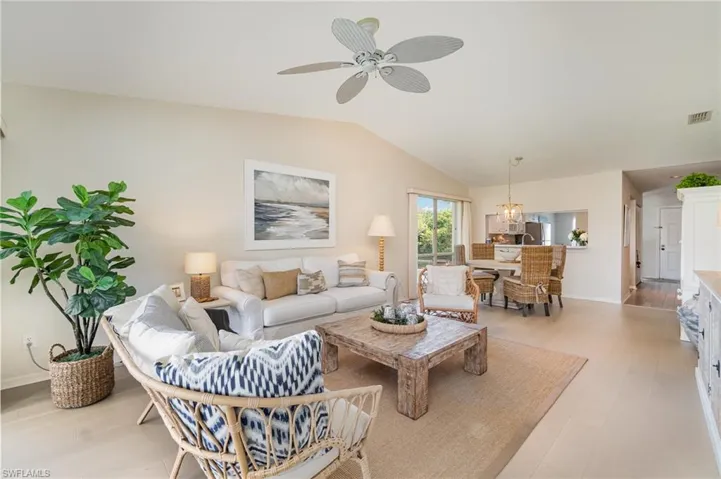 Living room featuring lofted ceiling, ceiling fan, light wood-style floors, and a chandelier