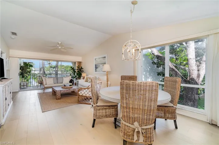 Dining area featuring ceiling fan, vaulted ceiling, light wood-type flooring, and suspended lighting