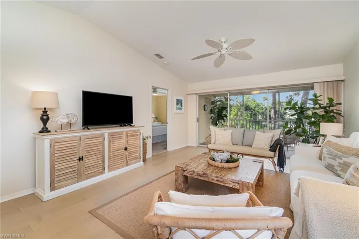 Living area featuring vaulted ceiling, light wood-style floors, and ceiling fan
