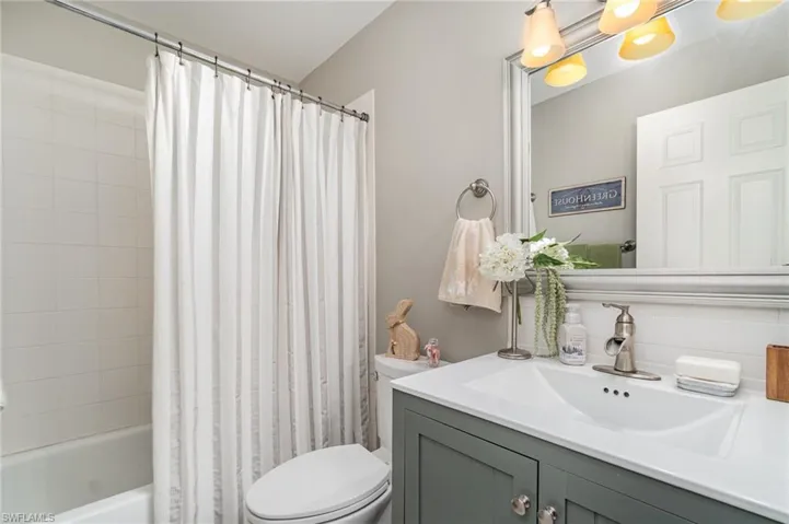 Bathroom featuring vanity, shower / bath combo, and backsplash
