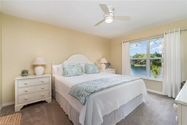 Bedroom with a water view, a ceiling fan, and dark colored carpet