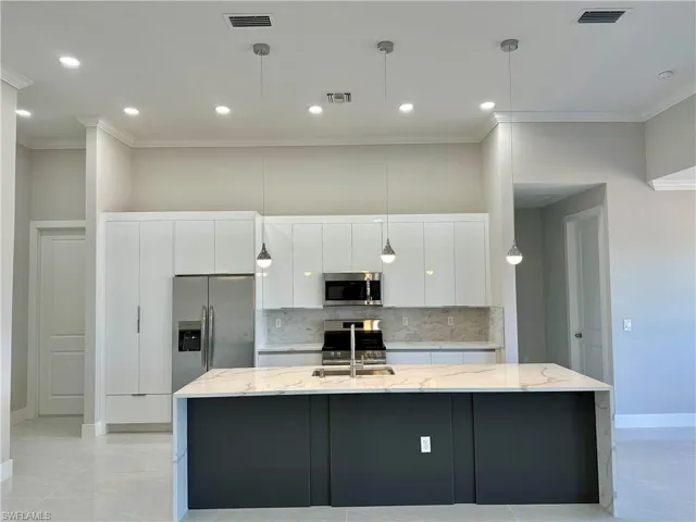 Kitchen with light stone countertops, tasteful backsplash, an island with sink, stainless steel appliances, and light tile floors