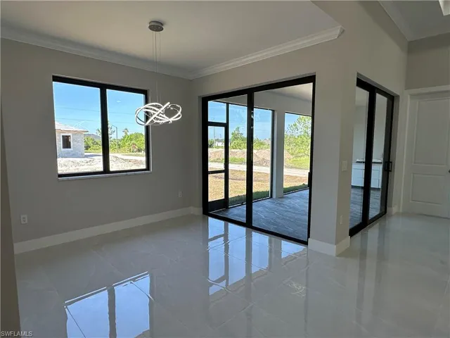 Empty room featuring tile floors, crown molding, and a notable chandelier