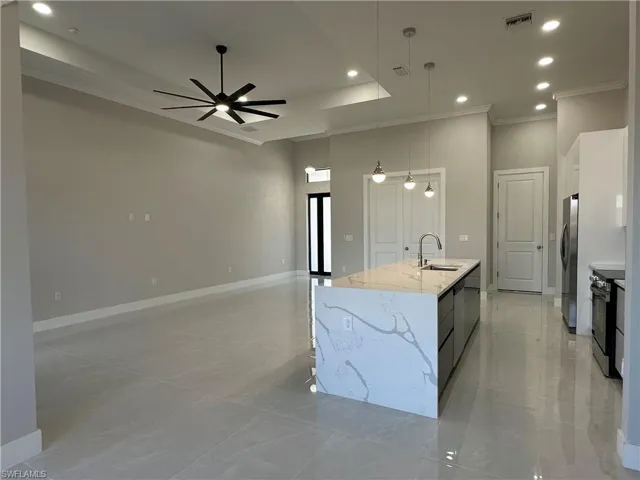 Kitchen featuring hanging light fixtures, ceiling fan, a kitchen island with sink, appliances with stainless steel finishes, and light tile floors