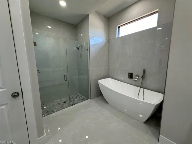 Bathroom featuring tile flooring, independent shower and bath, and tile walls
