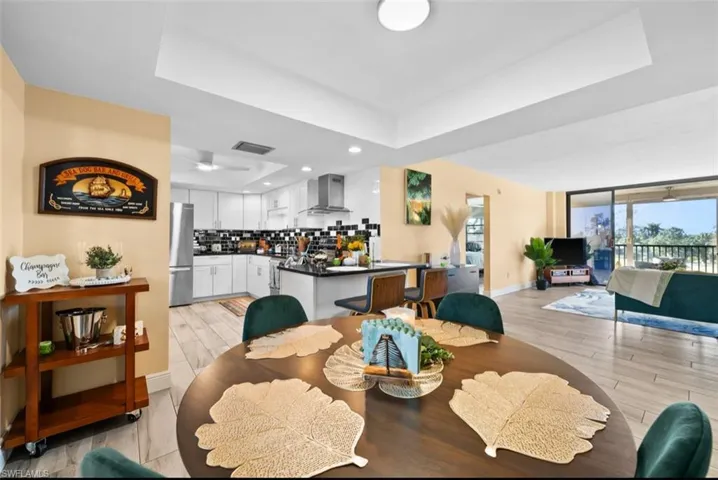 Dining area featuring a raised ceiling, wood finish floors, and recessed lighting