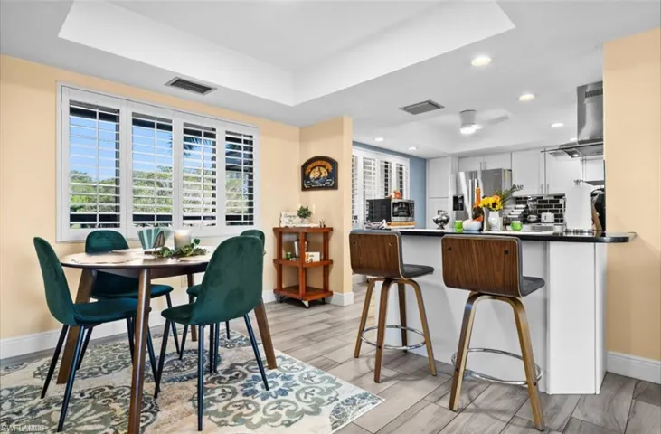 Dining area with a tray ceiling, wood finish floors, and recessed lighting