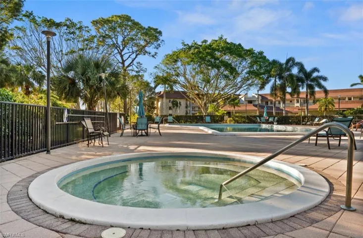Community pool featuring a hot tub, a patio, and a residential view