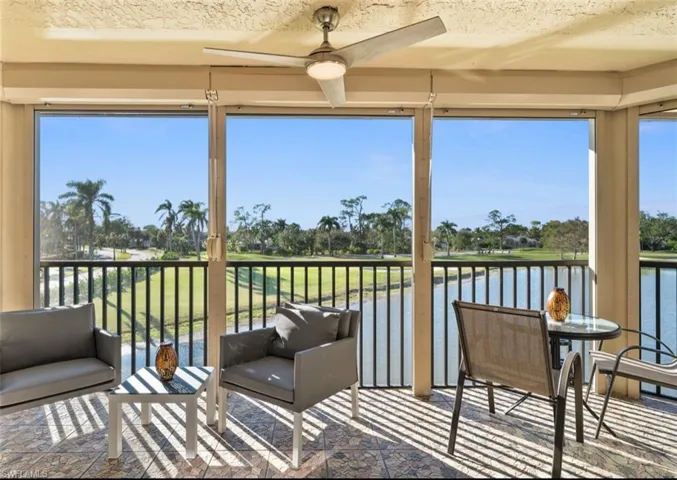 Sunroom / solarium with view of golf course, plenty of natural light, and a water view