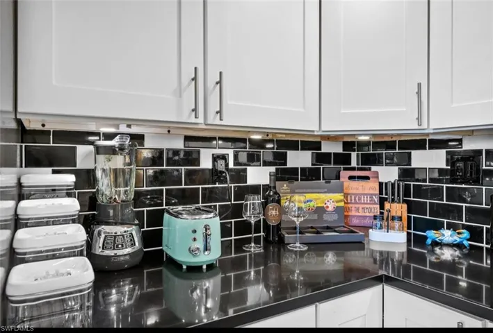 Kitchen view of white cabinetry and decorative backsplash