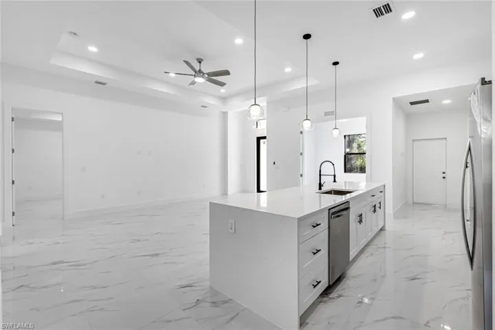 Kitchen featuring white cabinets, light stone countertops, pendant lighting, a ceiling fan, and stainless steel appliances