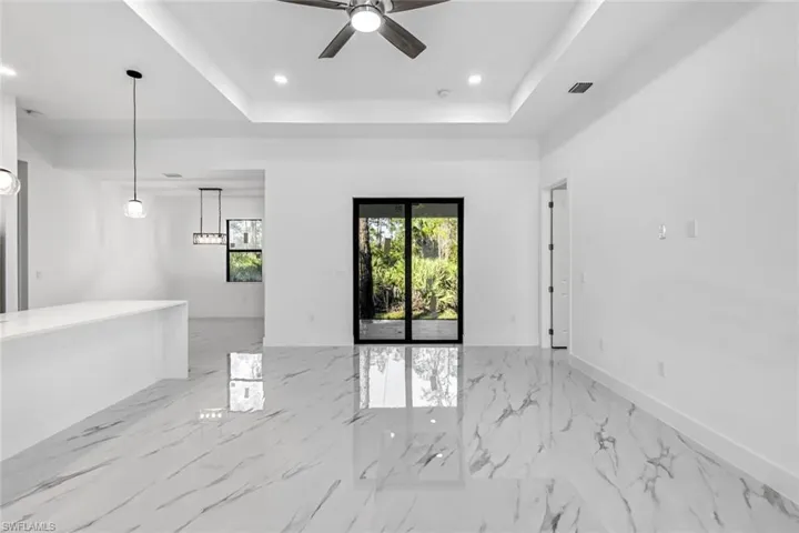 Unfurnished room featuring a tray ceiling, recessed lighting, a ceiling fan, and light marble finish flooring