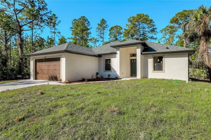 Prairie-style home featuring a front yard, stucco siding, a garage, driveway, and a shingled roof