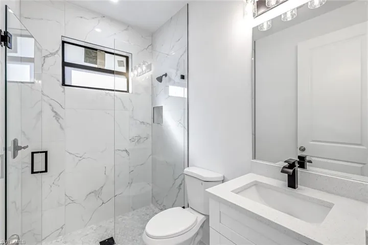Bathroom featuring vanity and a marble finish shower